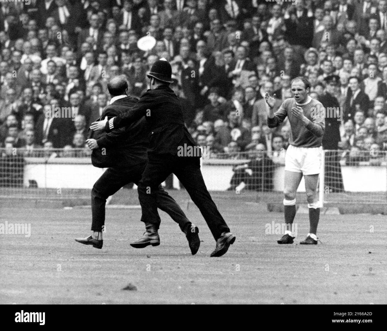 Finale di fa Cup 1966 Everton contro Sheffield mercoledì è stato un momento di folle entusiasmo durante la finale. Dopo l'eroe di Everton, Mike Trebilock segnò il suo secondo gol, questo tifoso precipitò sul campo, ma fu rimosso dalla polizia. Il giocatore dell'Everton nel tiro è Ray Wilson. 14 maggio 1966 Foto Stock