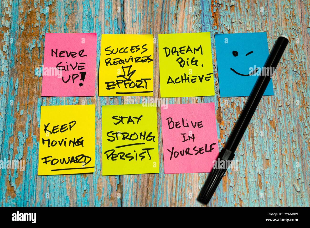 Pensieri motivazionali e positivi scritti sui post-it con un volto felice e un pennarello su un tavolo di legno rustico. Concetto di motivazione quotidiana. Foto Stock
