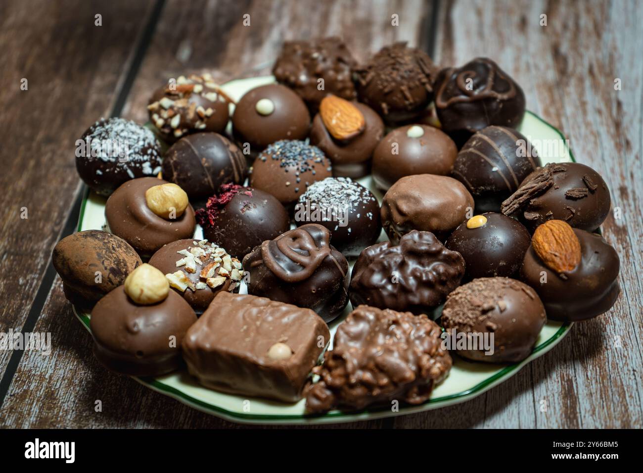 Assortimento di bonbon di cioccolato ripieni su un piatto su un tavolo di legno. Foto Stock