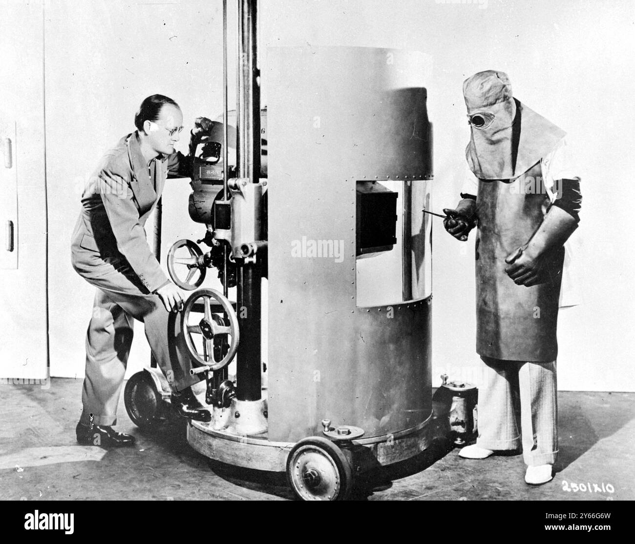 La telecamera protetta da un pesante scudo di piombo e lo scienziato nella sua tuta di materiale protettivo con una maschera di piombo pronta per il film 1937 Foto Stock