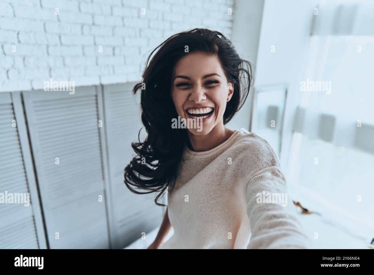 Sorriso sincero. Autoritratto di una giovane donna attraente che guarda la macchina fotografica e sorride mentre si trova in camera da letto a casa Foto Stock