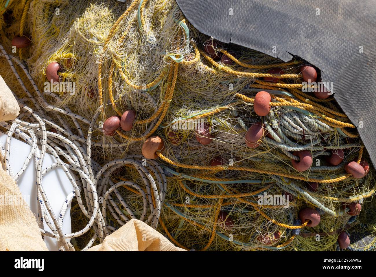 Reti da pesca gialle in un mucchio sulla costa nel porto. Boe tonde arancioni. Soleggiato giorno d'estate. Astrakeri, Corfù, Grecia. Foto Stock