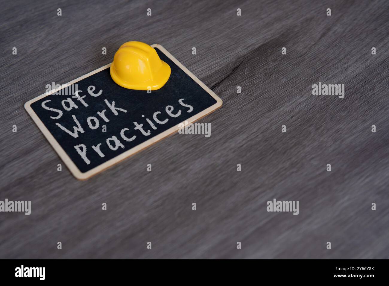 Piccola lavagna con il testo "pratiche di lavoro sicure" e elmetto giallo. Concetti di sicurezza, precauzione e standard sul luogo di lavoro. Foto Stock