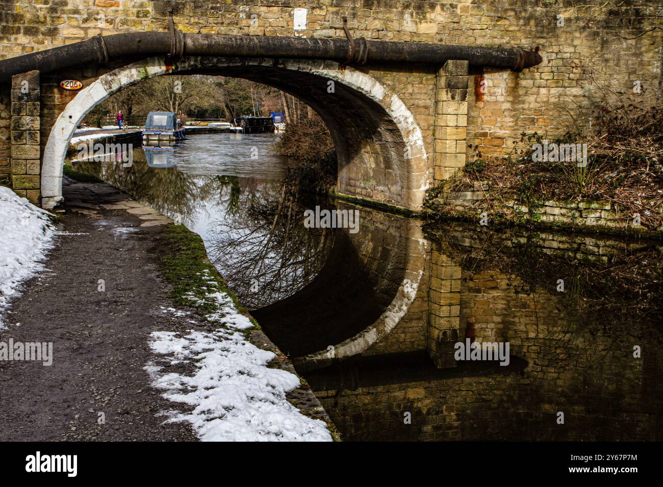 L'affascinante ponte sul canale si erge graziosamente riflesso nelle acque tranquille, mentre un'accogliente barca sul canale si trova nelle vicinanze. Foto Stock