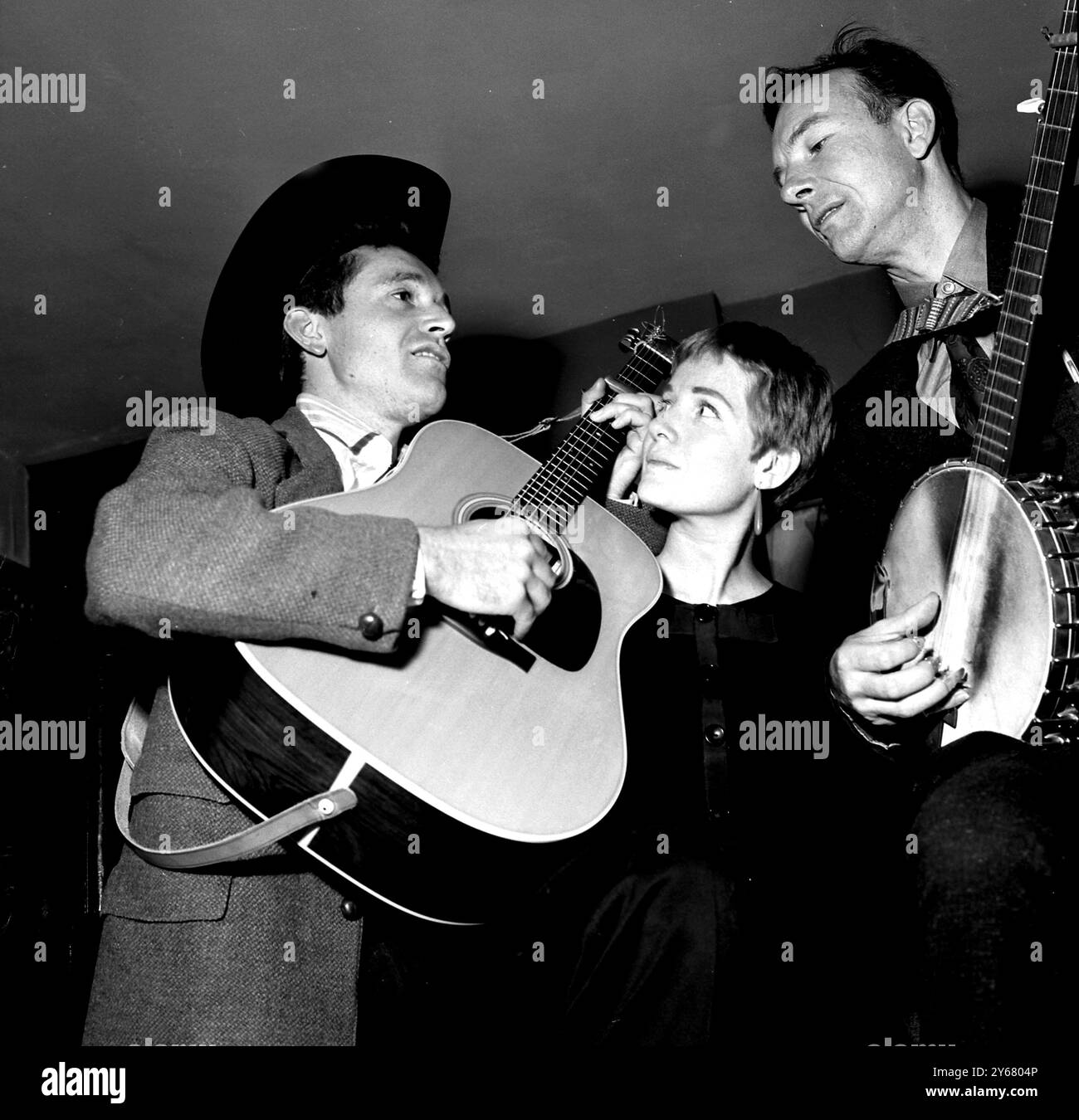 Jack Elliott (a sinistra) e Pete seeger (a destra) hanno una sessione di allenamento prima di iniziare il loro tour in Gran Bretagna. 'Hootenanney' è meglio conosciuta come musica folk, e seeger ha appena completato uno studio di due anni sul Folk Lore con sua moglie giapponese, Toshi. Nella foto del centro c'è June Elliott moglie di Jack che ha rinunciato alla carriera cinematografica per gestire suo marito. Londra - 27 settembre 1959 Foto Stock