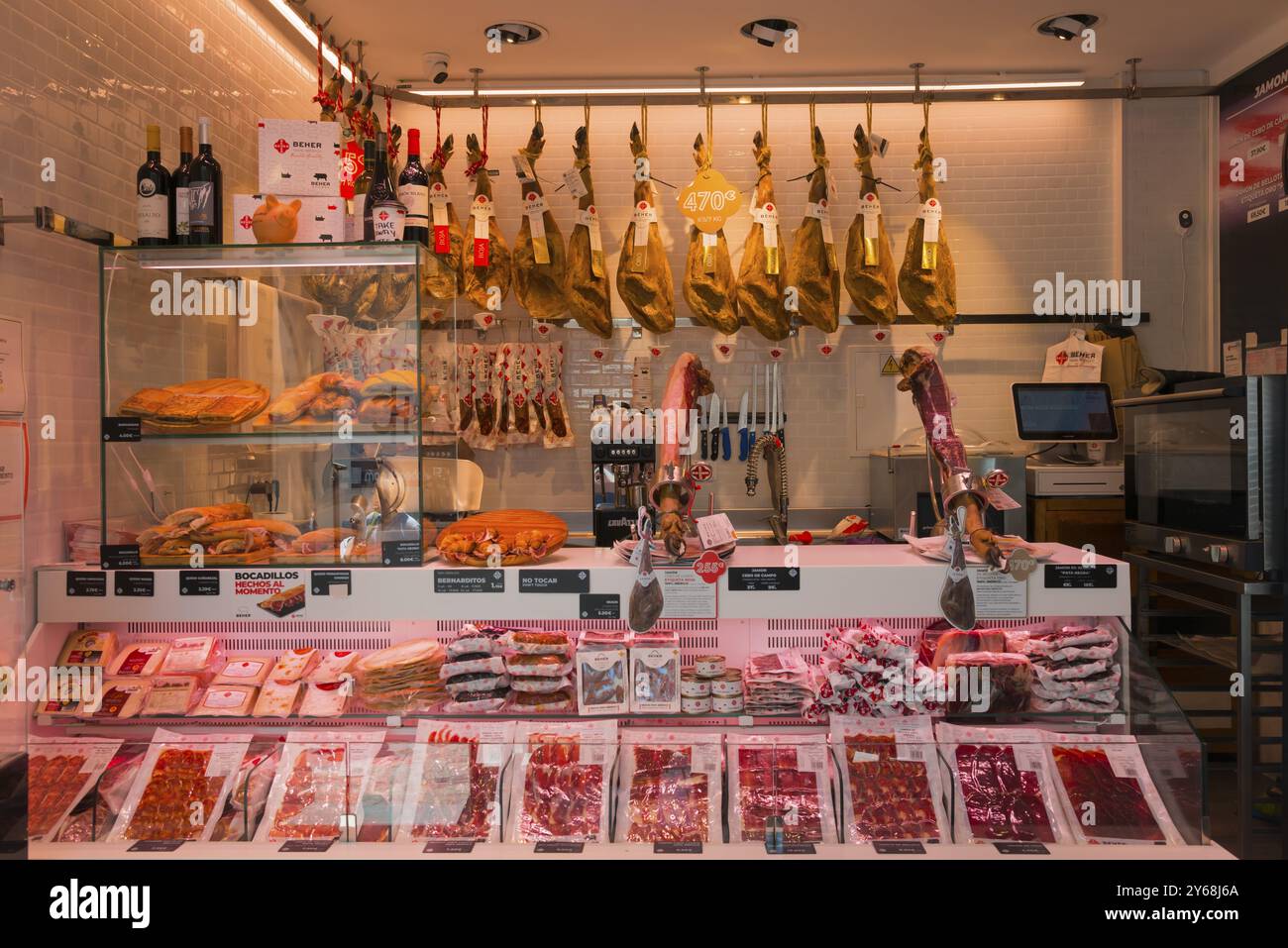 Moderna macelleria con bancone di carne, prosciutti appesi, salsicce e bottiglie di vino in esposizione, illuminata e ordinata, Nerja, provincia di Mala Foto Stock