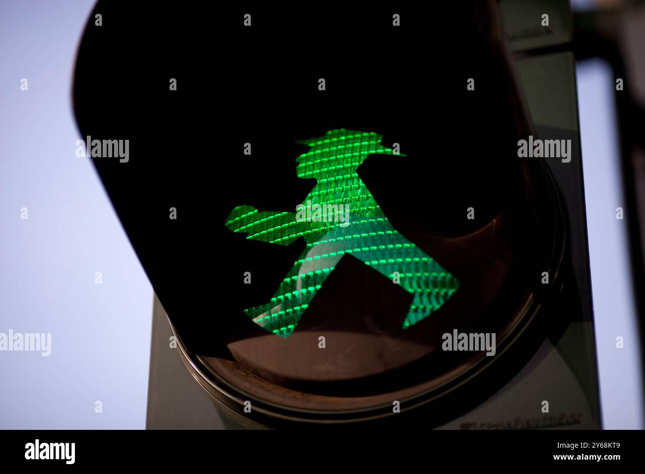 Un segnale verde per la zona pedonale di Ampelmännchen splende a Berlino Est, invitando gli escursionisti ad attraversare la strada in modo sicuro. Foto Stock