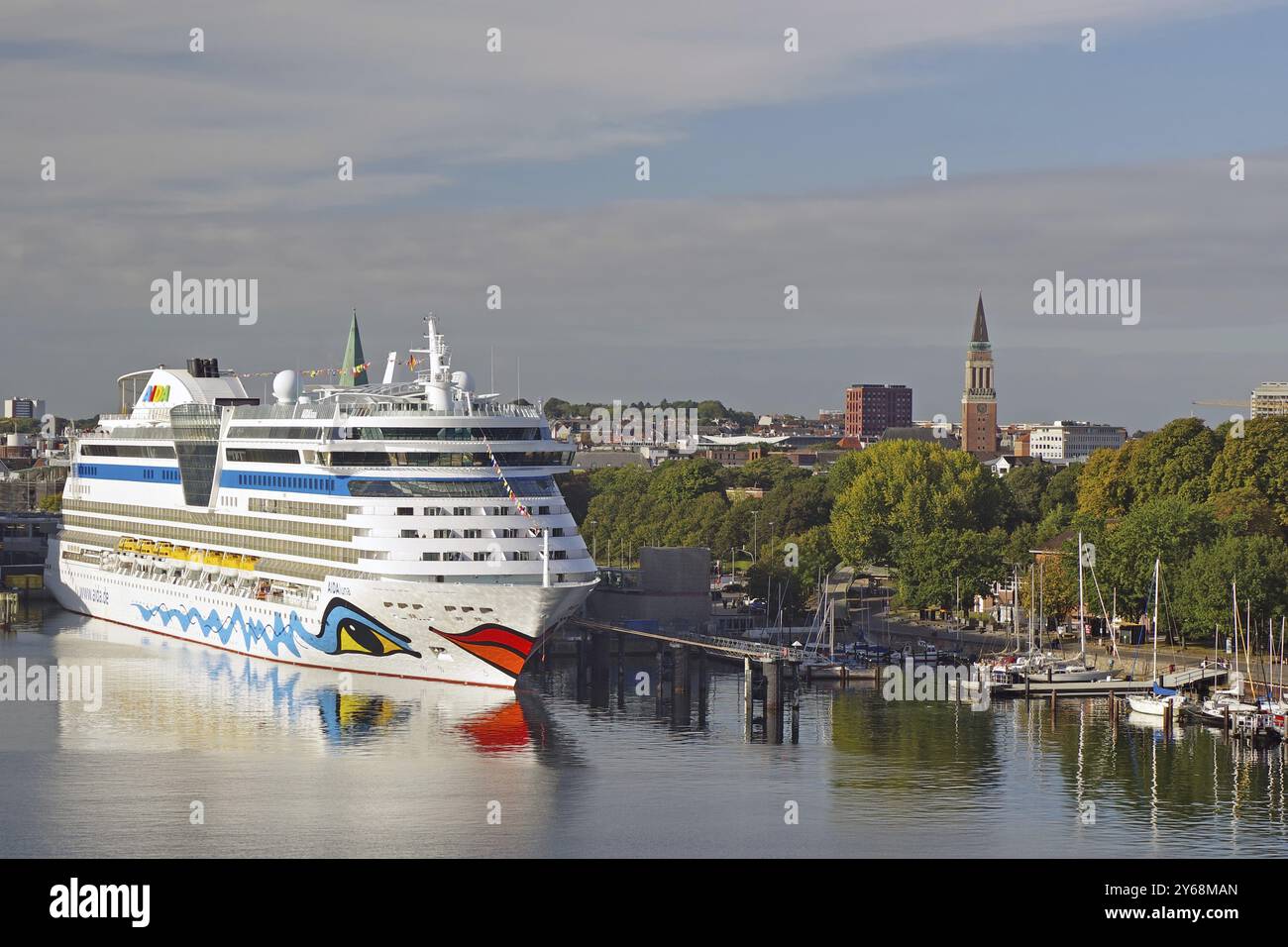 Grande nave da crociera bianca e blu nel porto, con edifici cittadini e una torre di chiesa sullo sfondo, il fiordo di Kiel, Kiel, Schleswig-Holstein, Germa Foto Stock