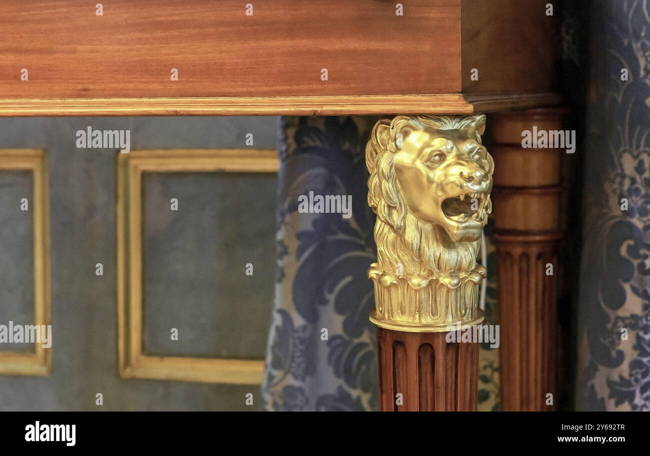 Testa di leone in bronzo sulla gamba di un antico tavolo in legno. Foto Stock
