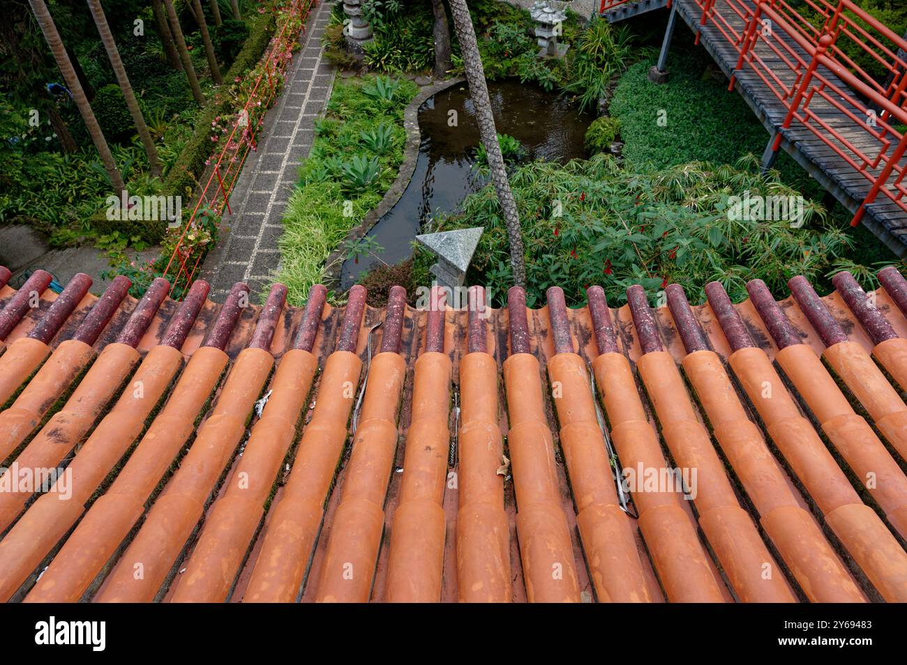 Tetto in terracotta che si affaccia sui lussureggianti sentieri del giardino e sul ponte rosso del Palazzo monte Foto Stock