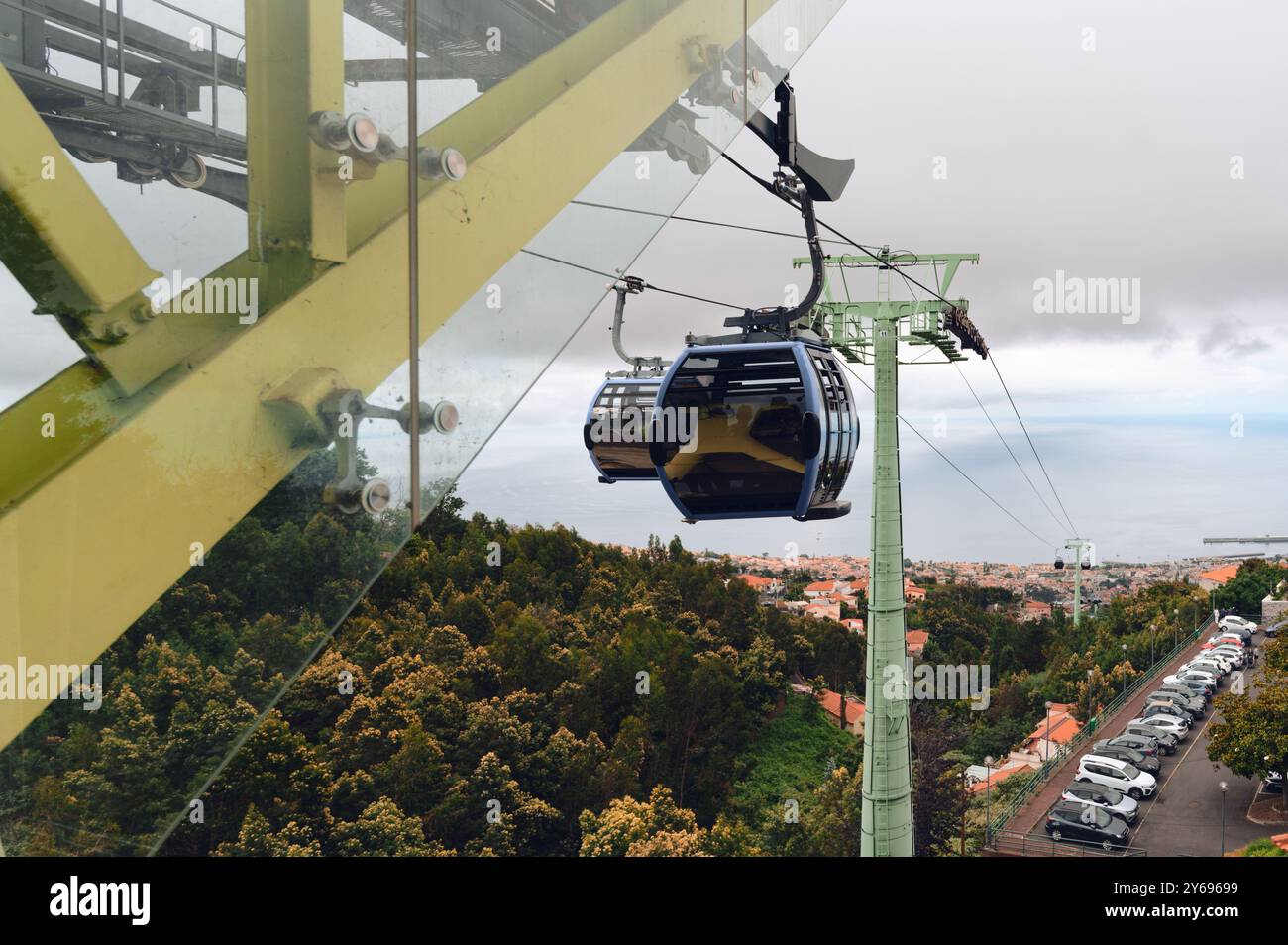 Funivia di Funchal che vola sopra le cime degli alberi, offrendo vedute della costa di madeira e del paesaggio urbano sottostante Foto Stock