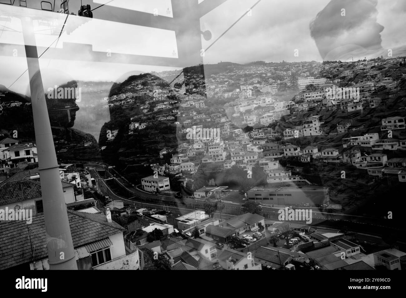 Riflessi e ombre si fondono con le case in collina in una vista ipnotica dalla funivia mentre passa un altro Foto Stock