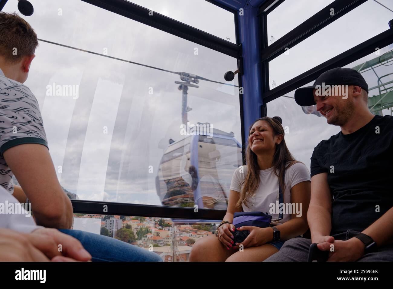 I turisti sorridenti si godono il giro in funivia di funchal, ammirando le viste mozzafiato di Madeira Foto Stock