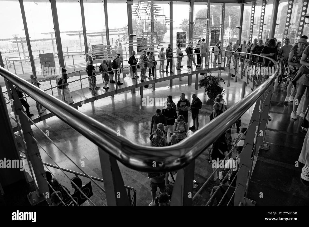 Vista monocromatica dei turisti in fila alla stazione della funivia di Funchal, catturando il flusso di movimento e l'attesa prima del loro viaggio panoramico Foto Stock