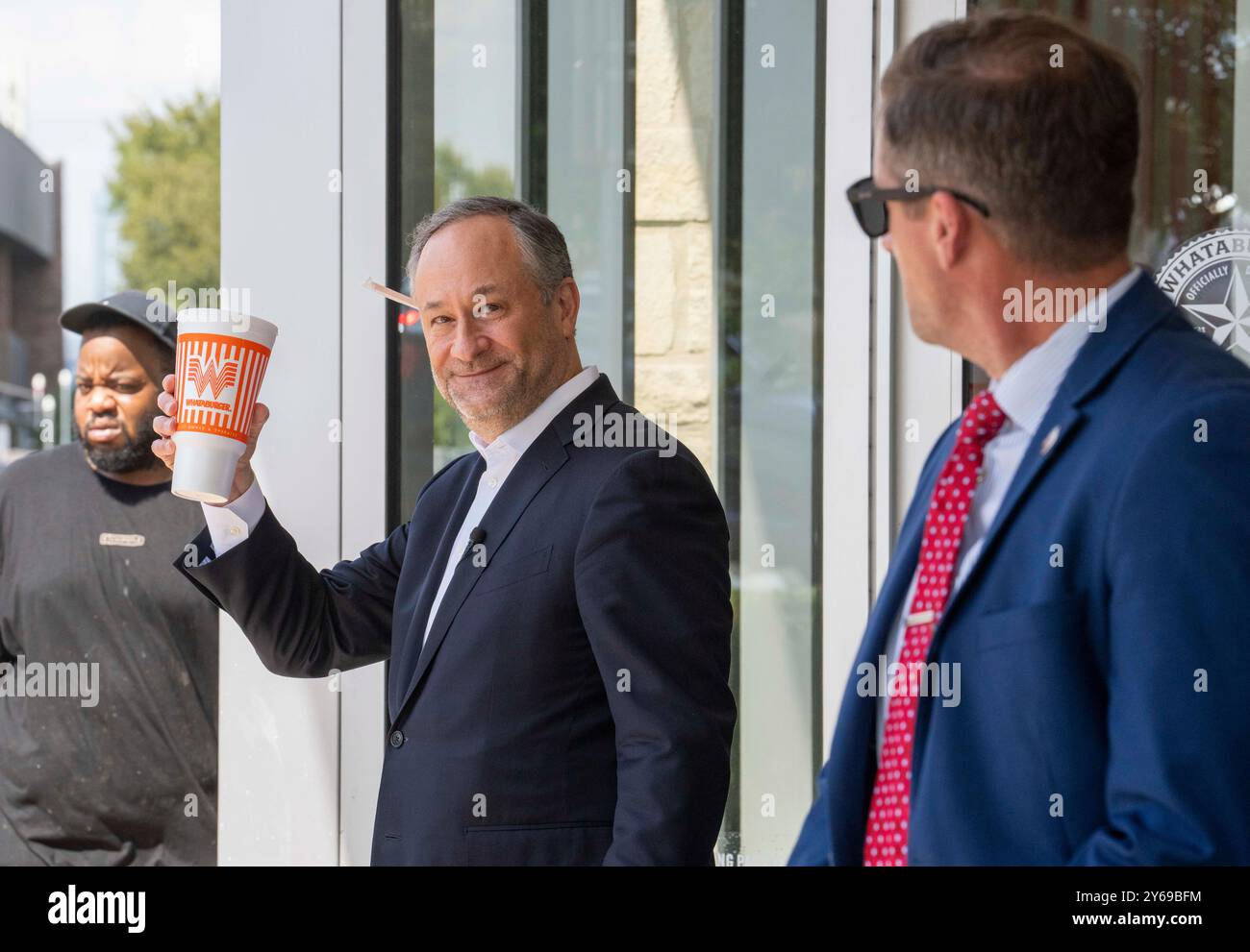 Austin, Texas USA, 24 settembre 2024: Il secondo gentiluomo DOUGLAS EMHOFF (centro) tiene una goccia dietro l'orecchio destro e una grande tazza di bibita analcolica in mano dopo aver fatto un ordine di hamburger da asporto in un ristorante Whataburger ad Austin prima di partire per un evento di raccolta fondi a Houston. Emhoff, marito del vice presidente degli Stati Uniti e candidato democratico alla presidenza Kamala Harris, ha raccolto diversi milioni di dollari in uno swing texano di due giorni per il biglietto Harris-Walz. ©Bob Daemmrich Foto Stock