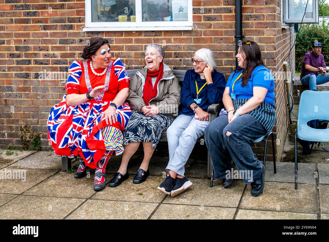 Un gruppo di persone siede a chiacchierare e ridere all'annuale Hartfield Village Fete, Hartfield, East Sussex, Regno Unito. Foto Stock