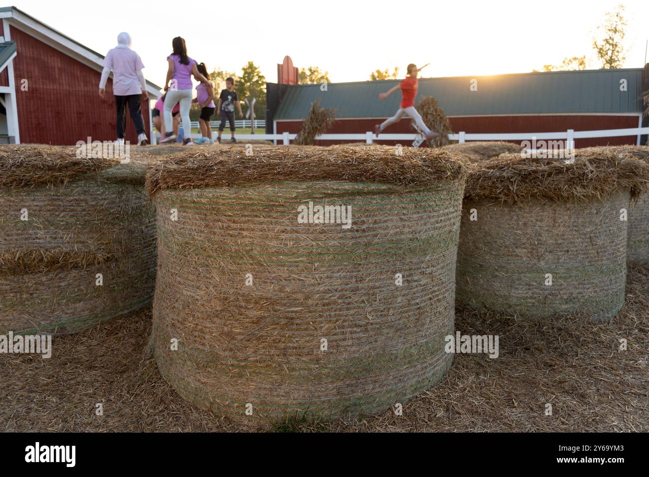 Bambini che giocano su balle di fieno al tramonto Foto Stock