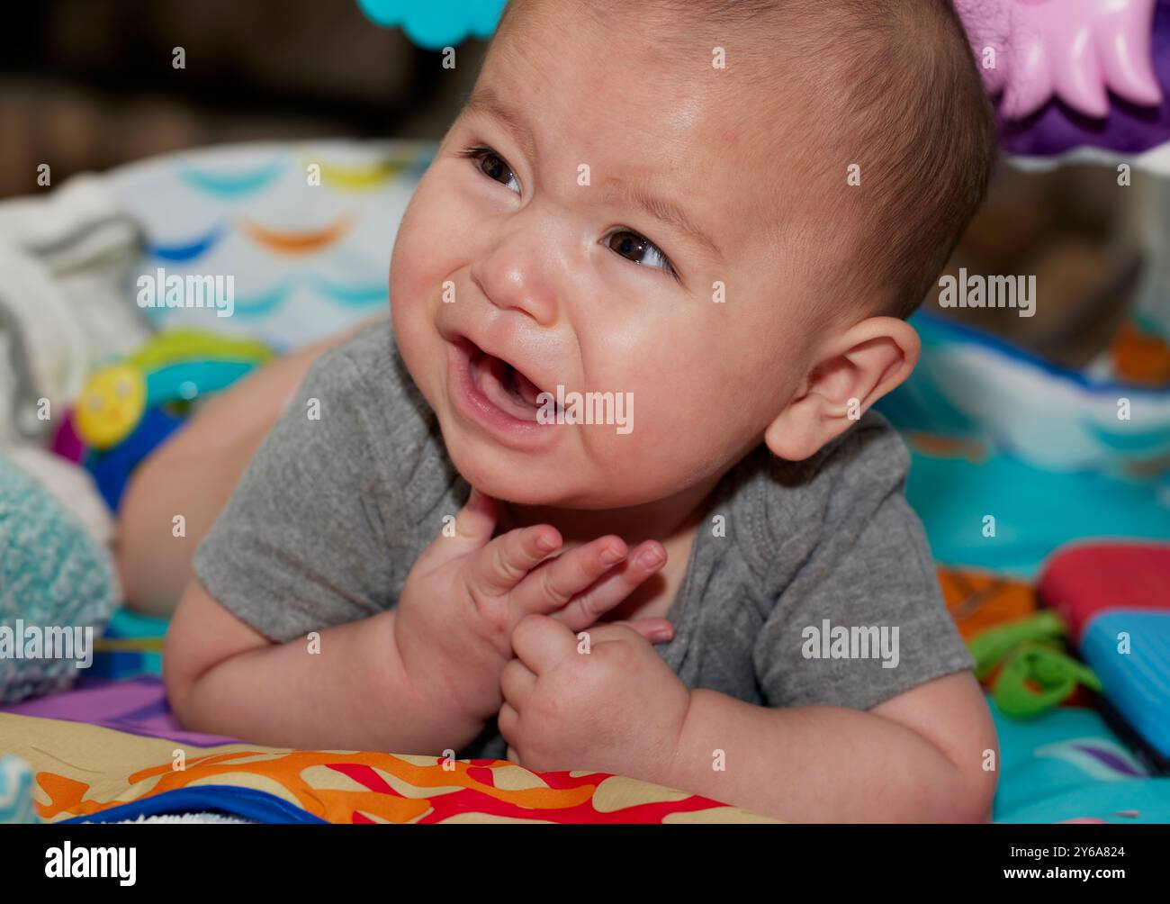 Primo piano di un simpatico bambino di sei mesi steso sullo stomaco e pronto a piangere Foto Stock