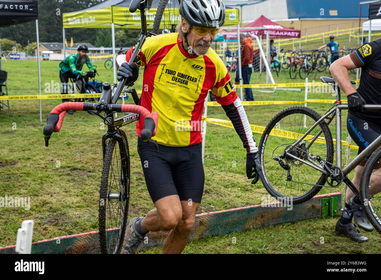 WA25662-00...WASHINGTON - Tom Kirkendall che porta la sua moto oltre le barriere, (invece di saltare), durante una gara ciclocross. Foto Stock