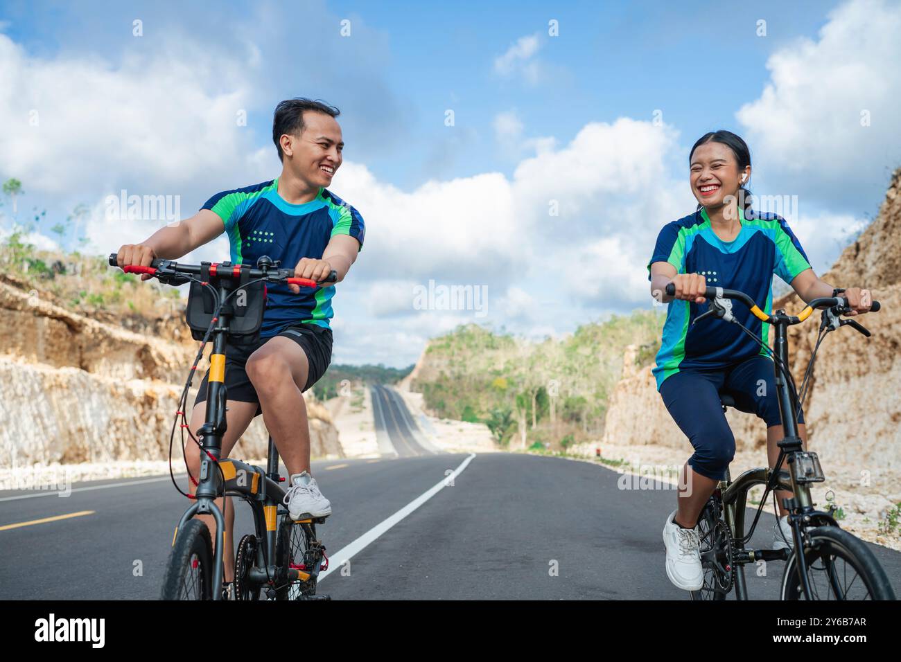 felice atleta femminile e maschile che pedala insieme Foto Stock