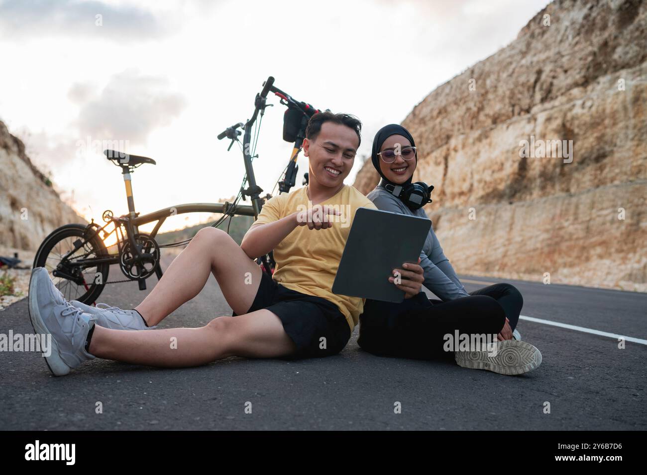motociclista maschile che usa il tablet e mostra un amico hijab Foto Stock