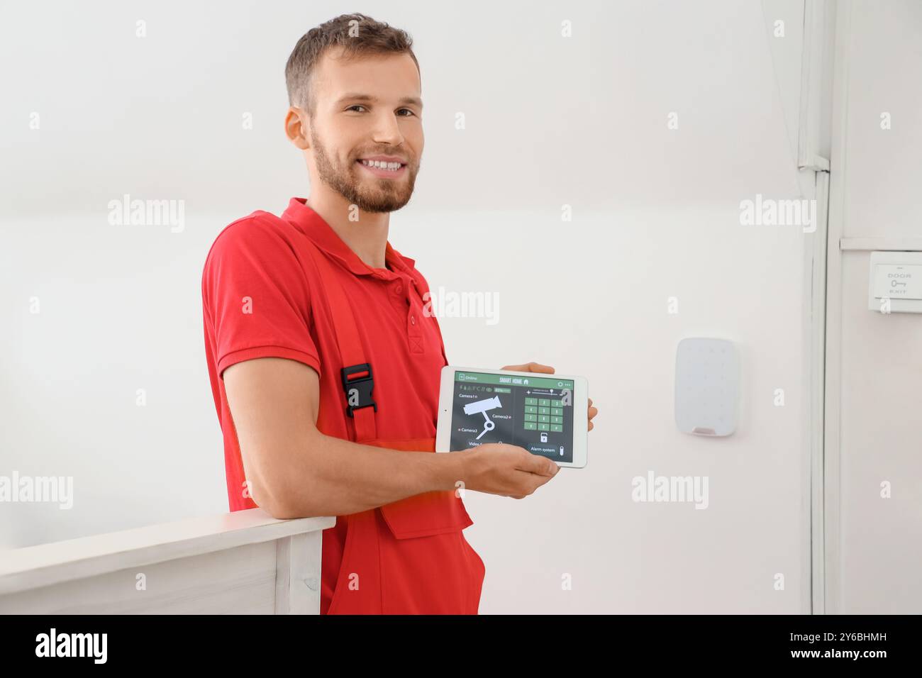 Lavoratore maschio che tiene un tablet computer con sistema di allarme installato in camera Foto Stock