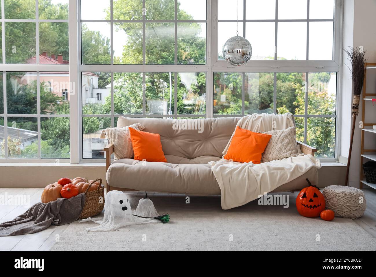 Elegante divano con ballo da discoteca e decorazioni di Halloween vicino alla finestra di casa Foto Stock