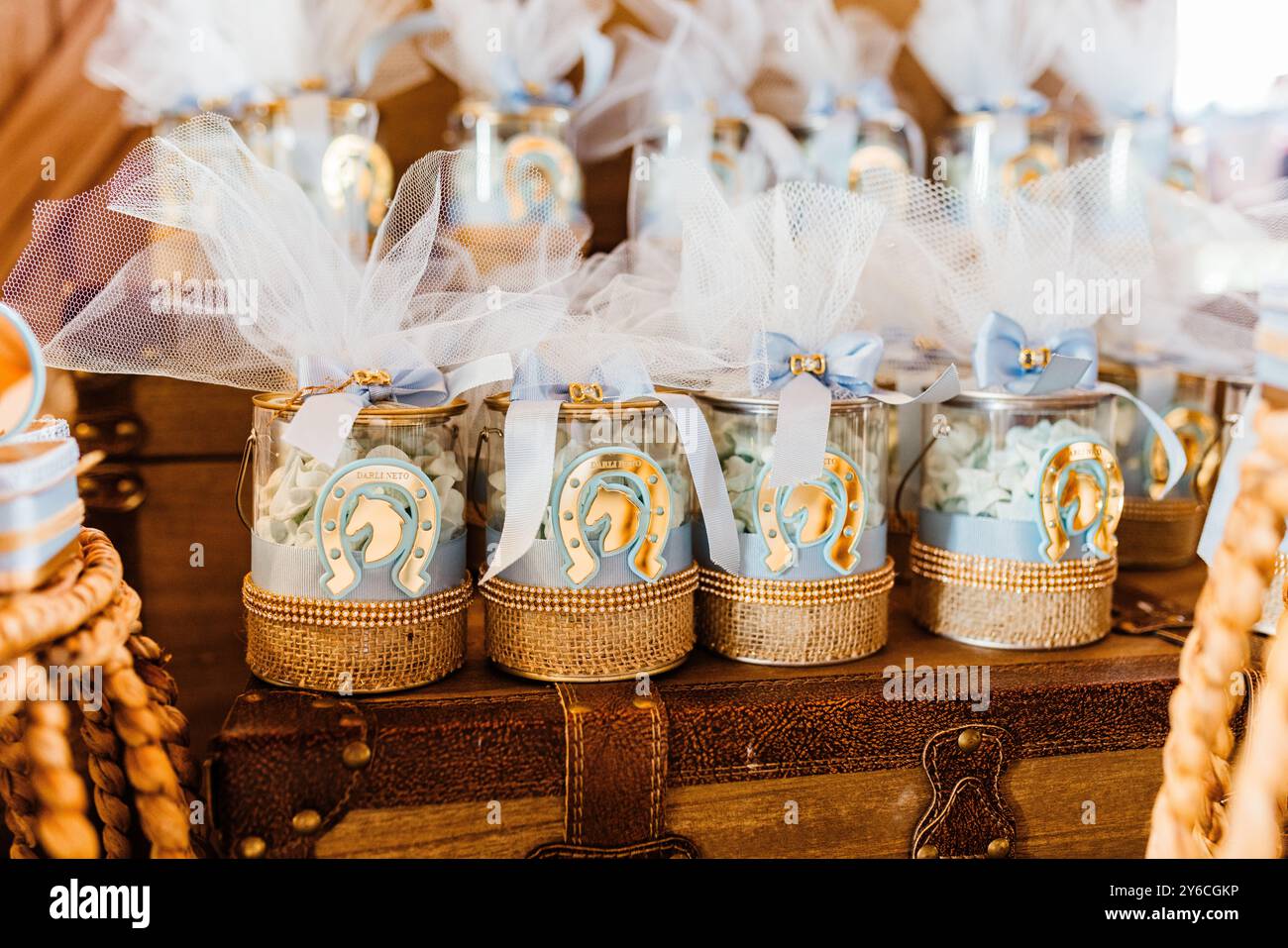 Omaggi da festa splendidamente decorati con accenti dorati e tulle su un tavolo in legno rustico, perfetti per una baby shower o un matrimonio. Foto Stock