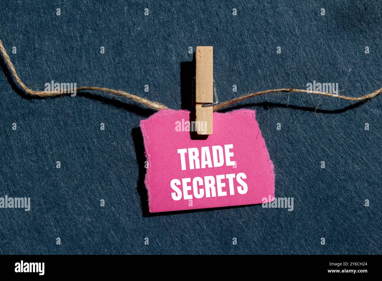 Messaggio segreto commerciale scritto su un pezzo di carta rosa strappato con sfondo grigio. Simbolo dei segreti commerciali concettuali. Copia spazio. Foto Stock