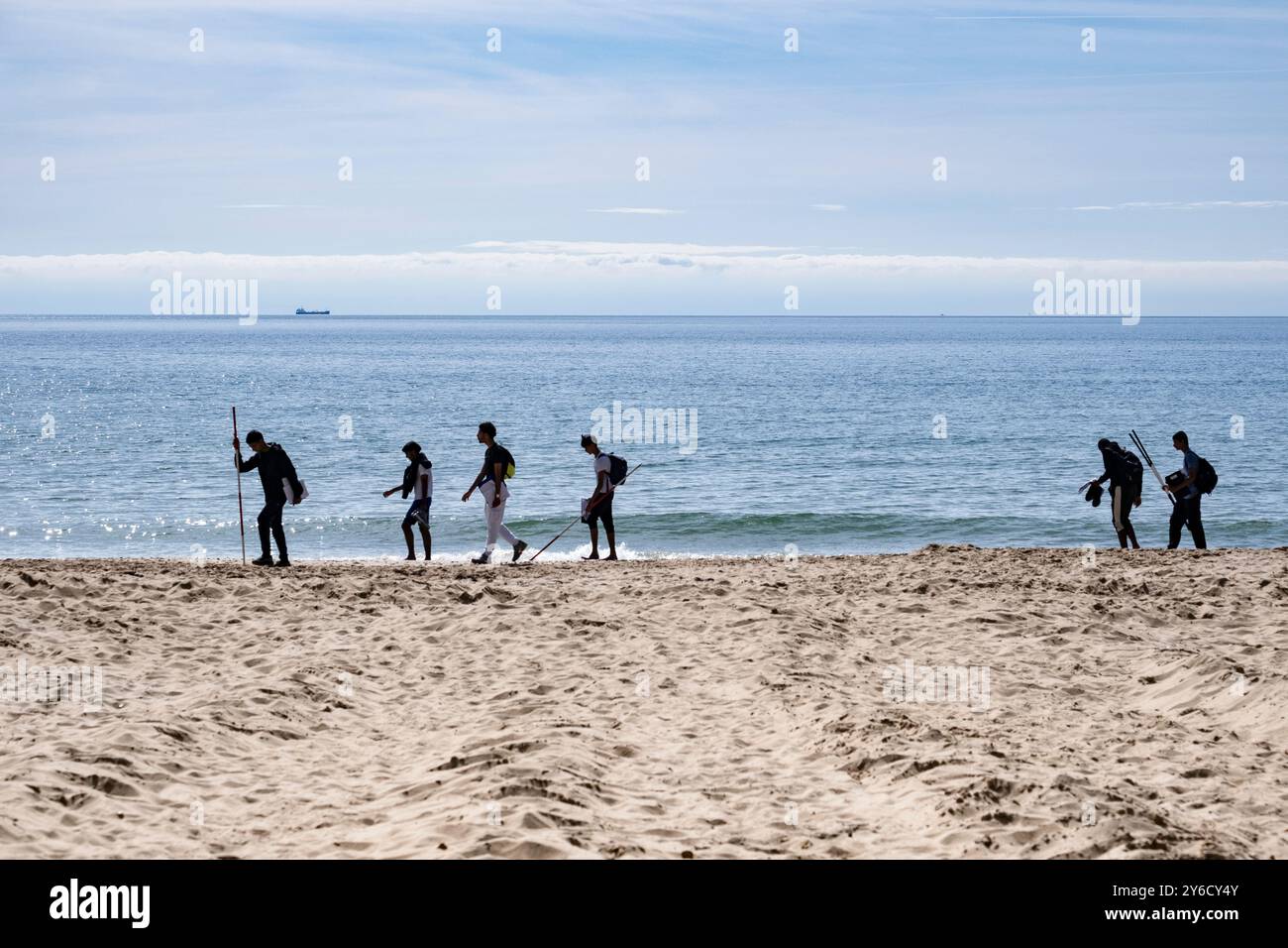 Una fila di persone che camminano lungo il litorale nella città costiera di Bournemouth, Dorset, Inghilterra. Foto Stock