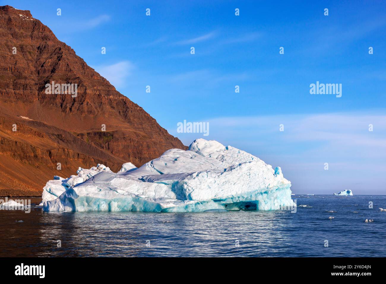 Iceberg blu, montagna di roccia rossa e cielo blu. Una giornata limpida nelle fredde acque dei fiordi di Scoresby Sund, in Groenlandia. Foto Stock