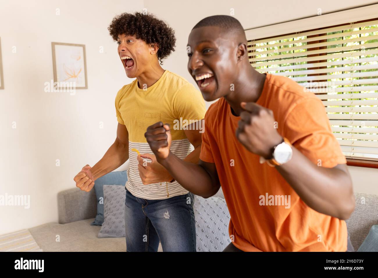 Festeggiando e festeggiando, due diversi amici maschi si divertono a casa Foto Stock