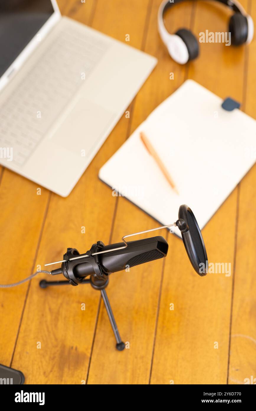 A casa, configurazione Podcasting con microfono, laptop, cuffie e blocco note su un tavolo in legno Foto Stock