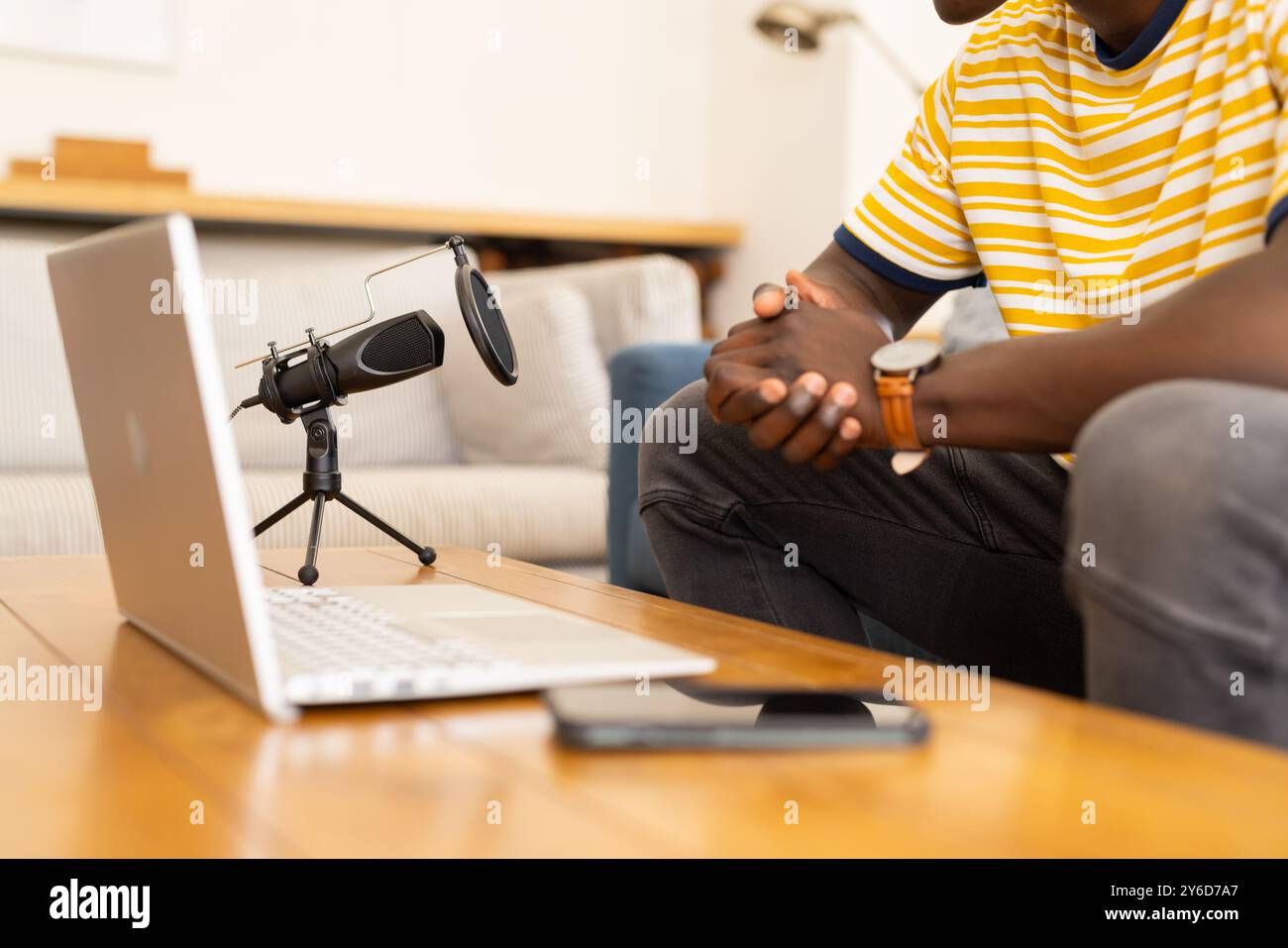 A casa, registrazione podcast, uomo afroamericano seduto con laptop e microfono sul tavolo Foto Stock