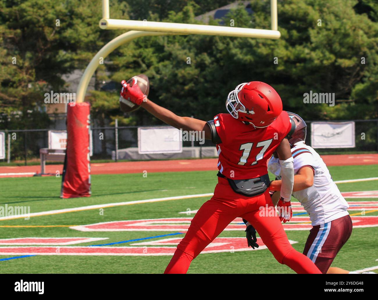 Primo piano di un wide receiver di football delle scuole superiori che effettua una cattura con una sola mano nella end zone durante una partita di football da dietro. Foto Stock
