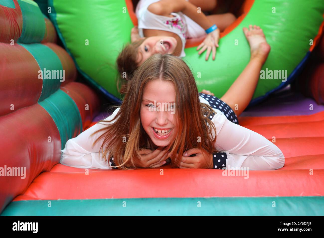 Ragazza carina in una colorata casa gonfiabile. divertirsi a una festa di compleanno con bambini sullo sfondo Foto Stock