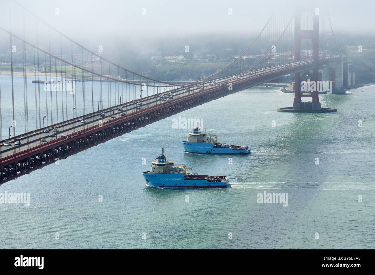 Le navi Ocean Cleanup Maersk Tender e Maersk Trader passano sotto un nebbioso Golden Gate Bridge. Foto Stock