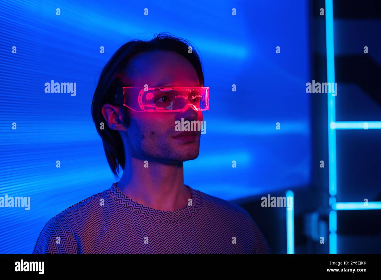 Uomo creativo futuristico con occhiali al neon intelligenti in una stanza al neon, sfondo blu neon metavalla la tecnologia digitale del mondo cyber Foto Stock