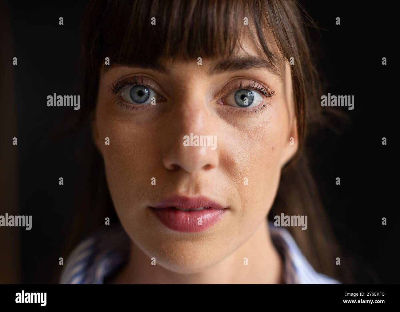 Primo piano di una donna con occhi blu e bangs, che guarda direttamente la fotocamera Foto Stock
