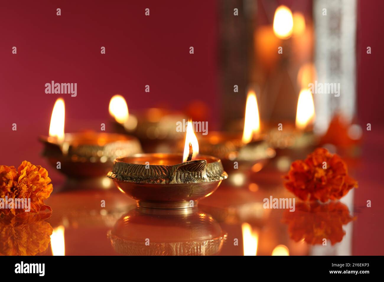 Festa Diwali. Lampade Diya e splendidi fiori su sfondo colorato, primo piano Foto Stock