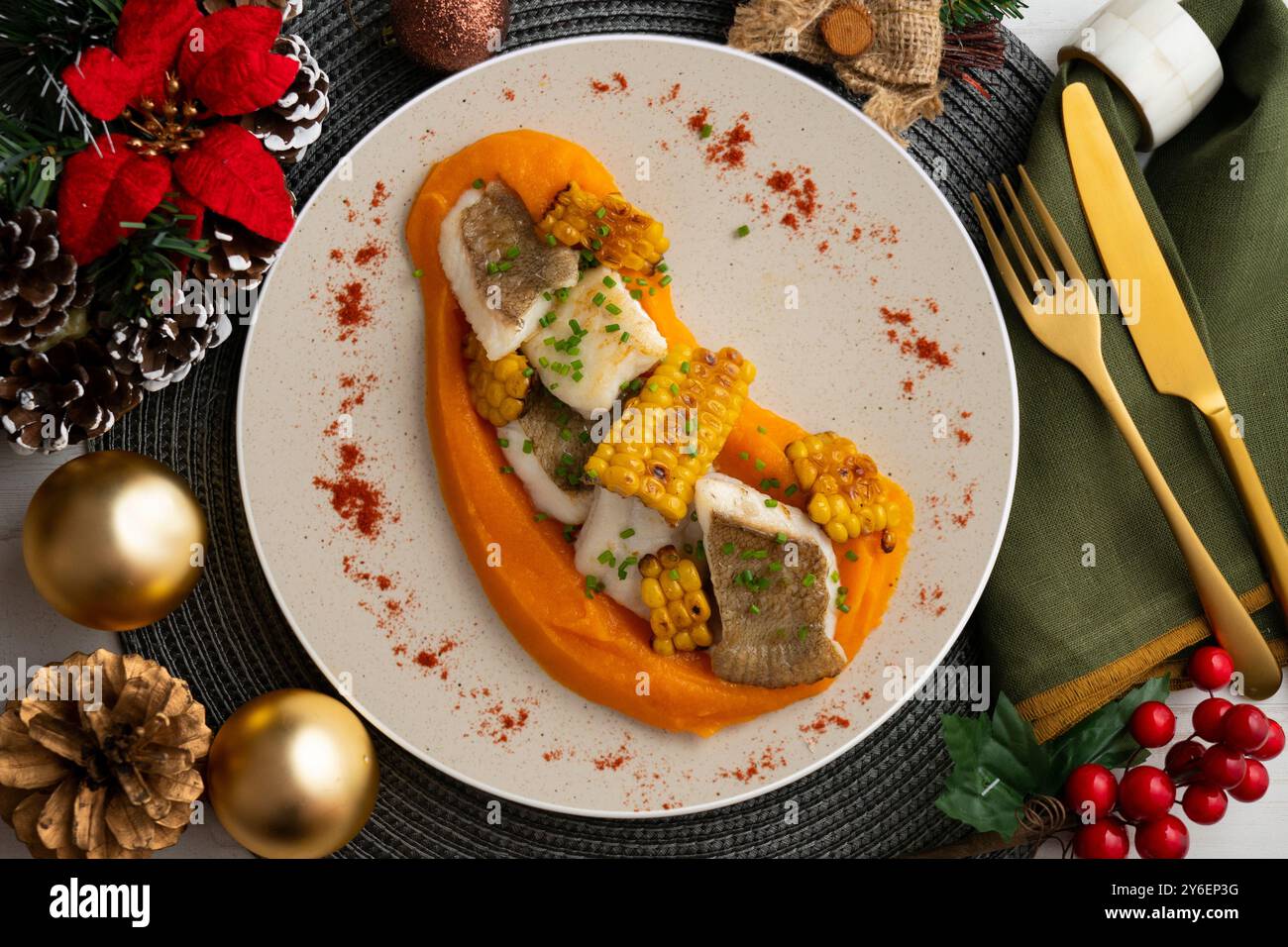 Delizioso pesce sogliola con crema di carote e mais. Tavolo con vista dall'alto e decorazioni natalizie. Foto Stock