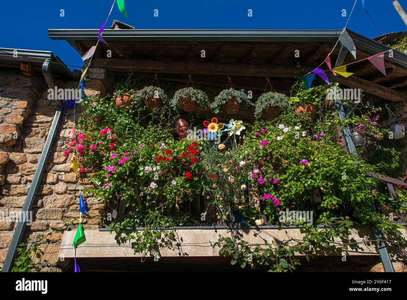 Villager sorride dal suo balcone coperto di fiori, dalla scena stradale, dal villaggio di Montesinho, dal parco naturale di Montesinho, dall'area di Tras-os-Montes nel nord del Portogallo Foto Stock