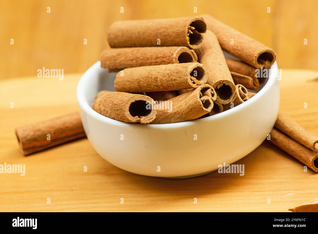 Cinnamomum verum, bastoncini di cannella in una ciotola bianca su fondo di legno Foto Stock