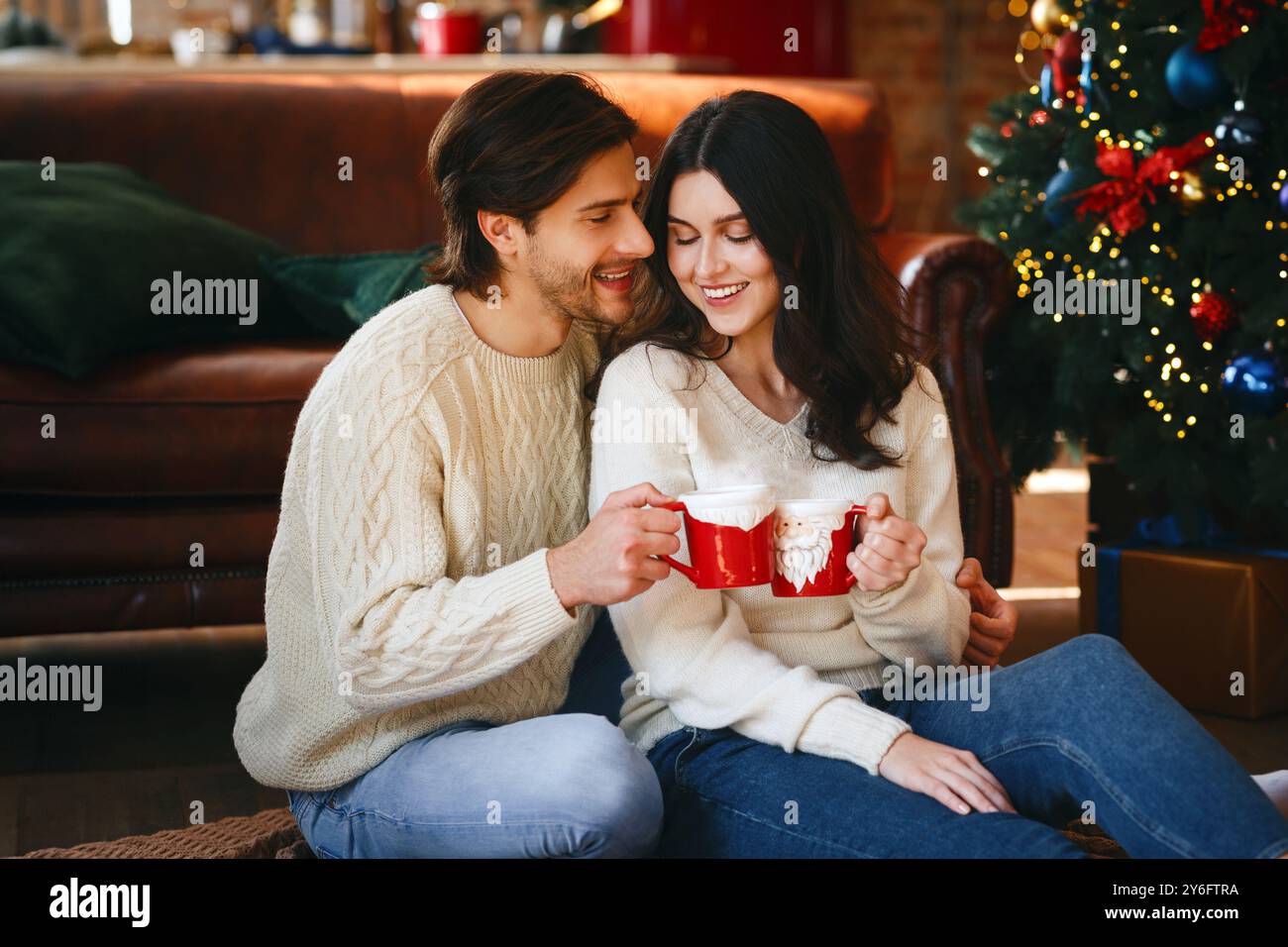Coppia innamorata di avere il cacao natalizio accanto all'albero di Natale Foto Stock