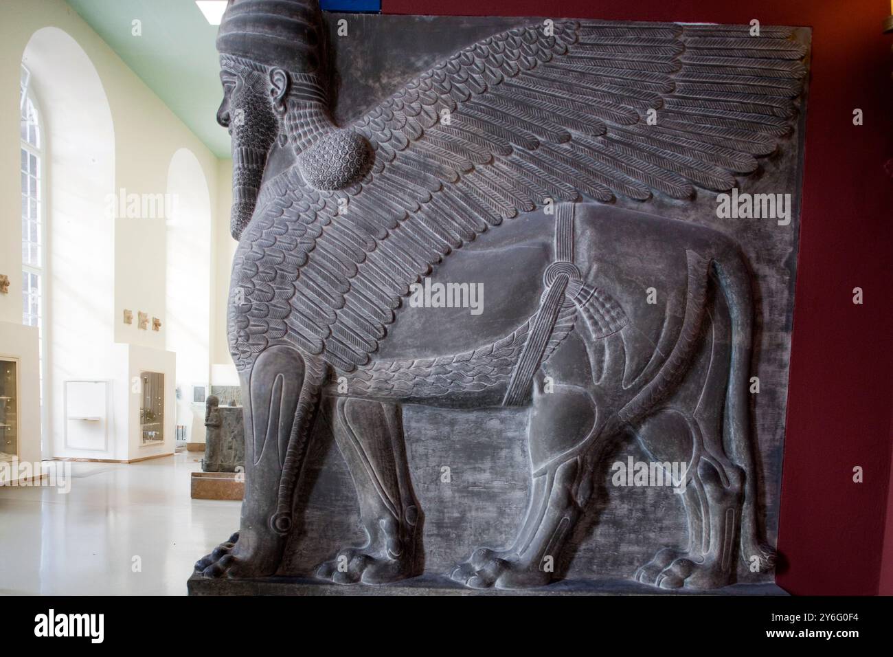 Una massiccia figura di leone alato assiro con testa umana si trova nel Museo di Pergamo, attirando visitatori a Berlino, in Germania. Foto Stock