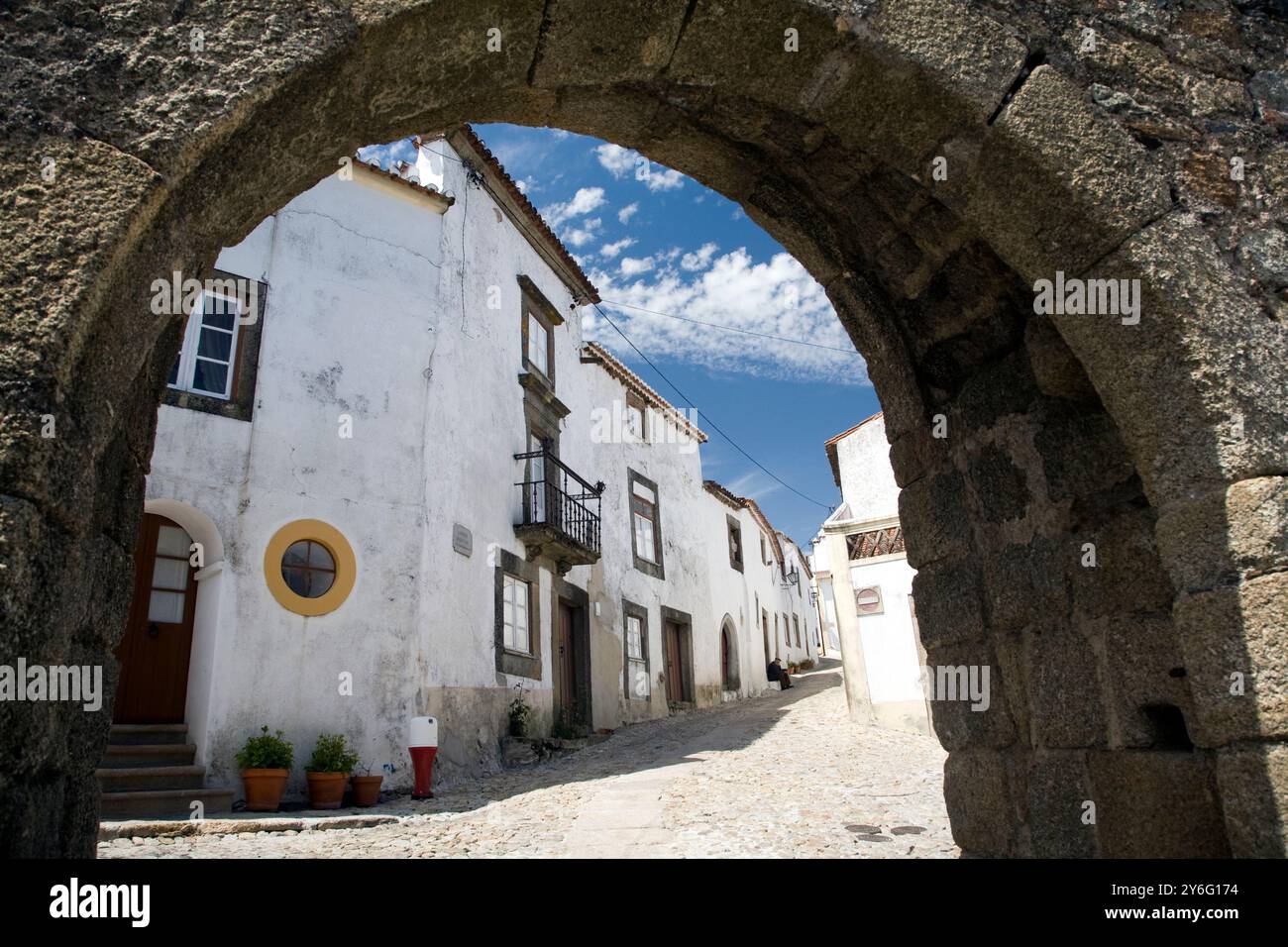 El arco de la muralla de Marvão en Portugal rivela casas blancas y un cielo despejado en un día luminoso. Foto Stock