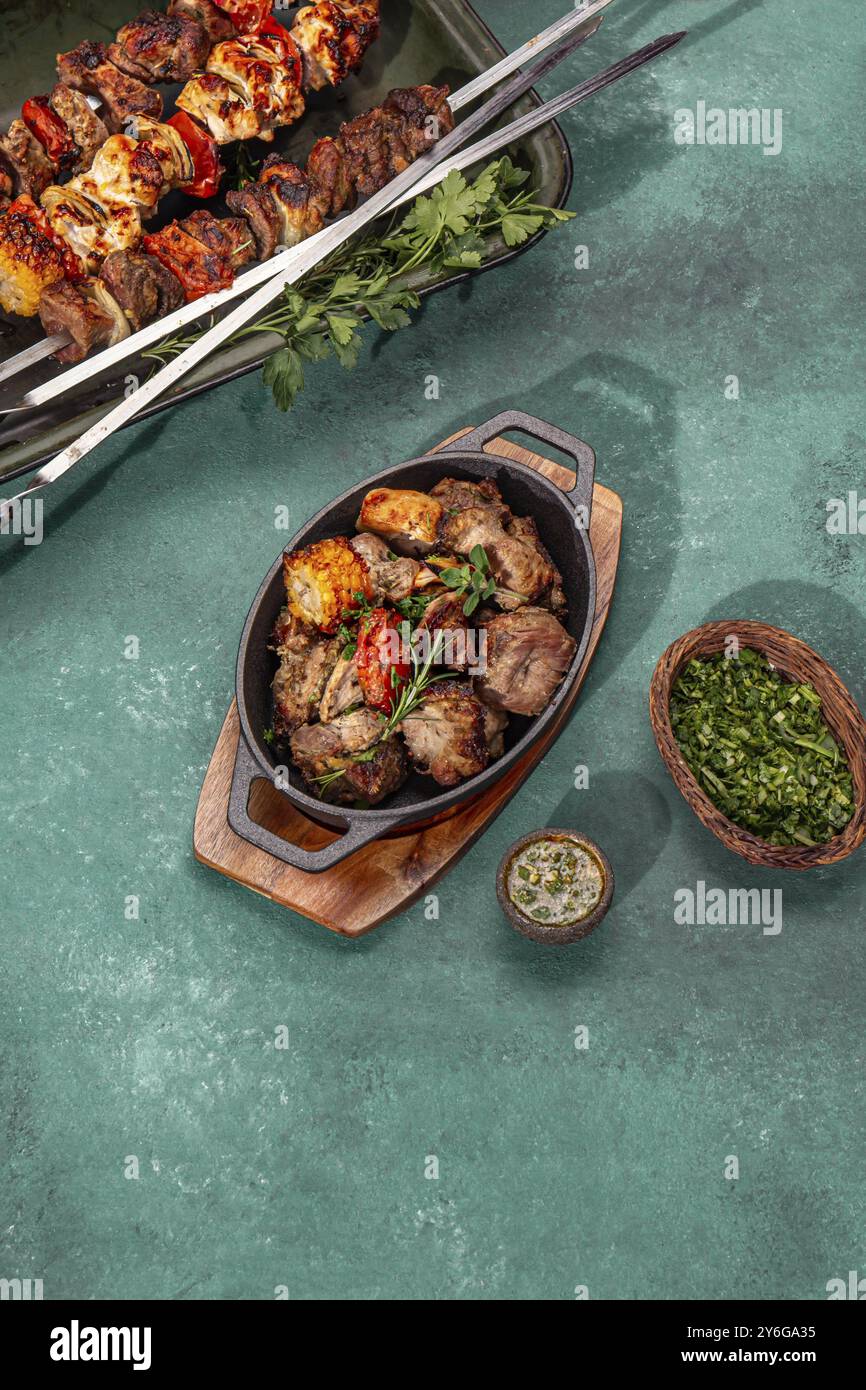 Cibo, carne grigliata alla griglia, maiale, pollo e verdure su una teglia in ghisa. Spiedini grigliati su sfondo giallo in legno. Vista dall'alto Foto Stock