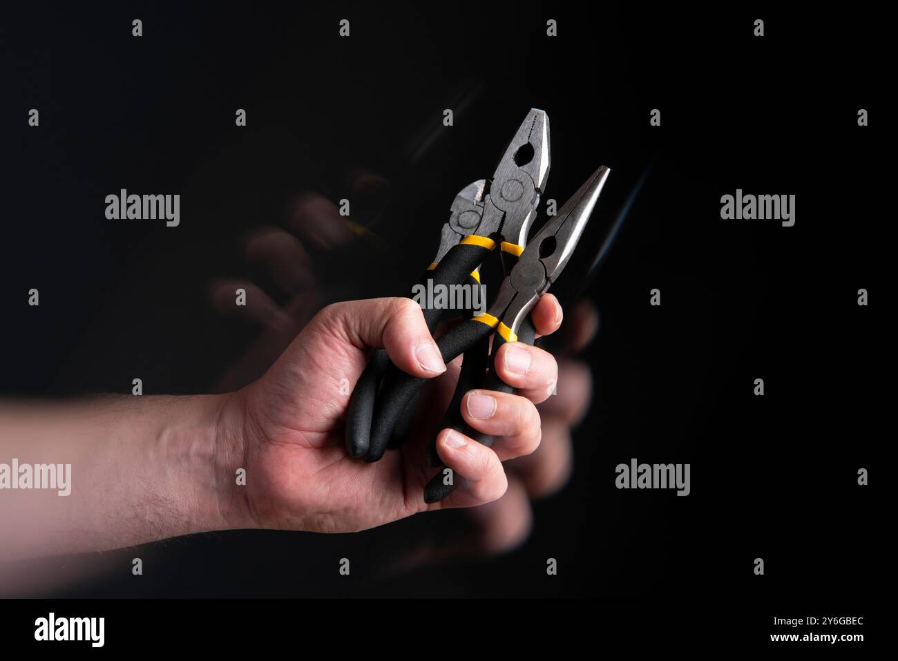 Primo piano della mano dell'uomo che tiene in mano tre diverse pinze tagliacavi con effetto di movimento su sfondo nero Foto Stock