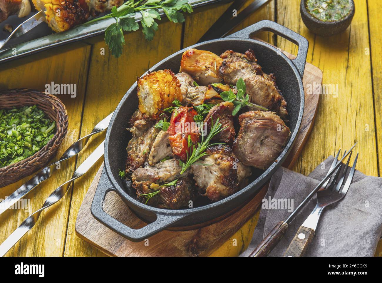 Cibo, cibo, carne grigliata alla griglia, maiale, pollo e verdure su una teglia in ghisa. Spiedini grigliati su sfondo giallo in legno. Vista dall'alto Foto Stock