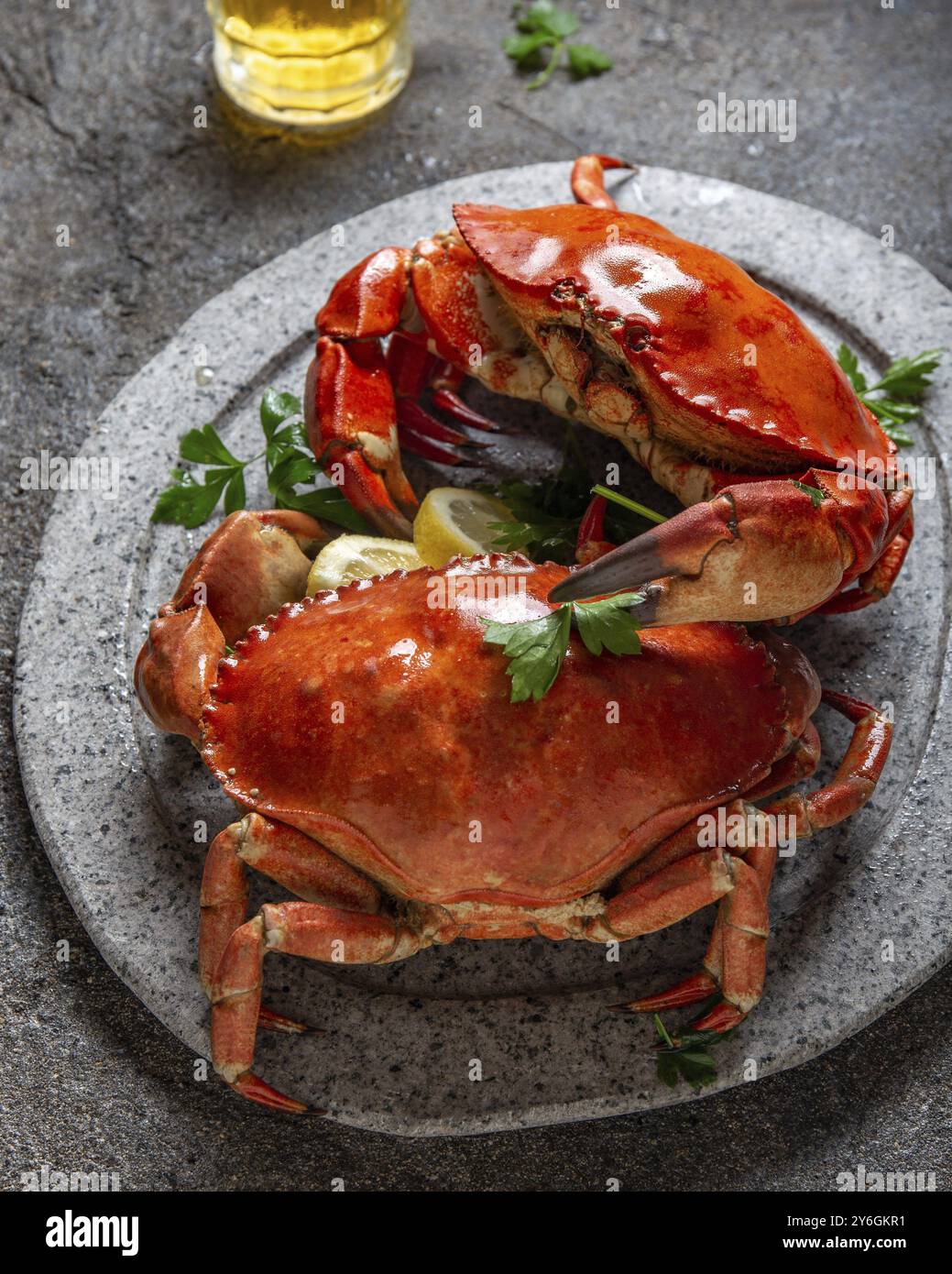 Cibo, cibo, granchi interi cotti su piatto bianco con limone e birra. Sfondo grigio in cemento. Vista dall'alto Foto Stock